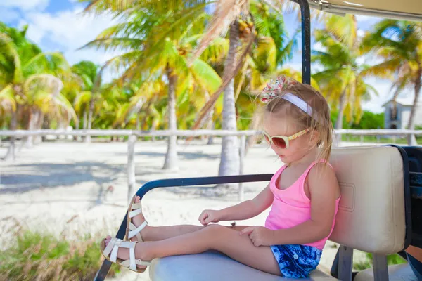 Petite fille mignonne assise dans une voiture de golf dans un bosquet tropical — Photo