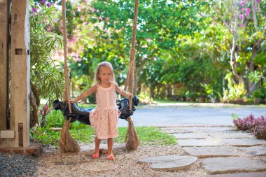 rahat, güzel, çiçekli bir avlu bir salıncak üzerinde sallanan küçük kızla
