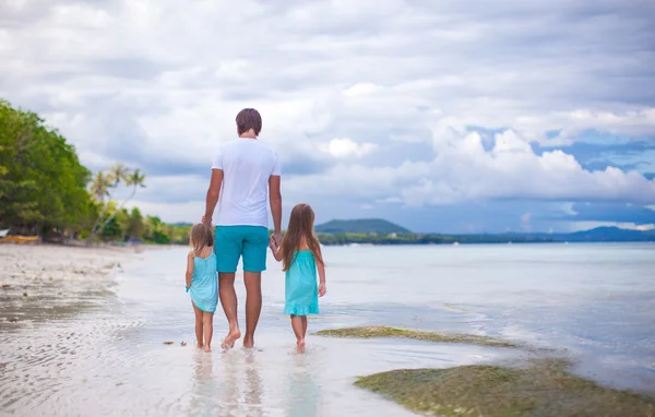 Vista trasera del padre y sus dos hijas caminando junto al mar — Foto de Stock