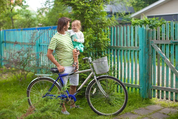 Unga far och söta lilla dotter cykla runt gården — Stockfoto