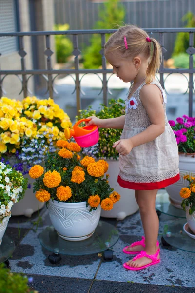 Lilla barn girl vattna blommor med en vattenkanna — Stockfoto