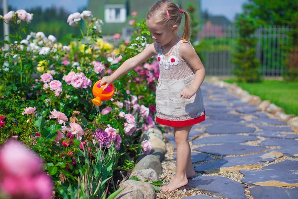 Bedårande söt flicka vattna blommor med en vattenkanna — Stockfoto