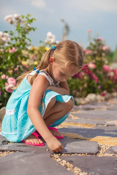 Cute small girl drawing on the sidewalk with chalk in the yard — Stock Photo, Image