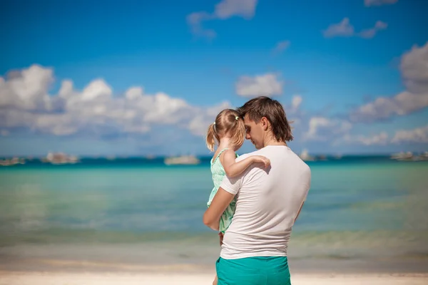 Portret van een klein meisje knuffelen met papa op het strand — Stockfoto