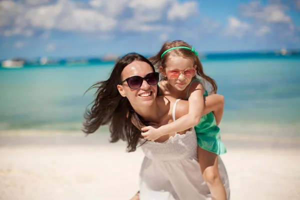 Joven hermosa madre y su adorable hija pequeña se divierten en la playa tropical — Foto de Stock