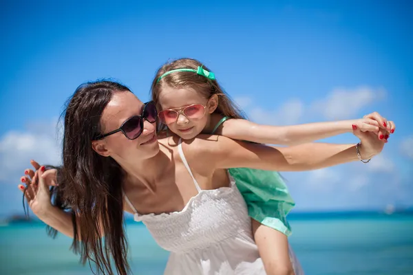 Young beautiful mother and her adorable little daughter have fun at tropical beach — Stock Photo, Image