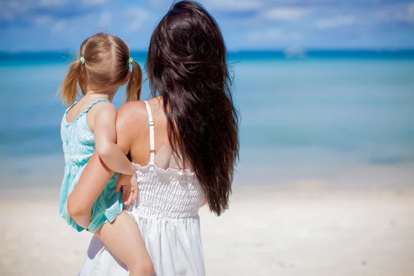 Vista trasera de la madre y su pequeña hija mirando al mar en la playa tropical — Foto de Stock