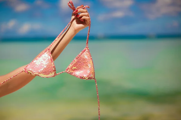 Woman's hand holding pink bra background the sea — Stock Photo, Image