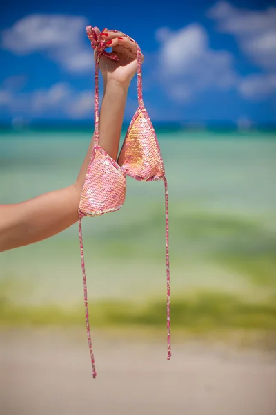 Mão da mulher segurando fundo sutiã rosa o mar — Fotografia de Stock