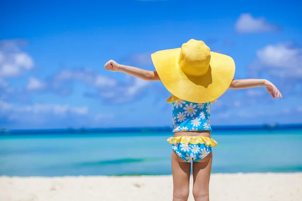 Zadní pohled na holčičku ve velkých klobouku při pohledu na moře na pláži s bílým pískem — Stock fotografie