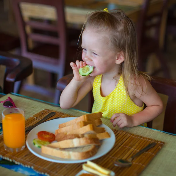 Cute little girl having breakfast at resort restaurant — Stock Photo, Image