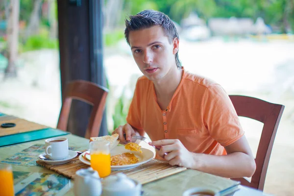 Young man having breakfast at resort restaurant — Stock Photo, Image