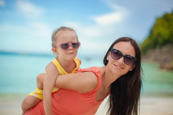 Young beautiful mother and her adorable little daughter have fun at tropical beach — Stock Photo, Image