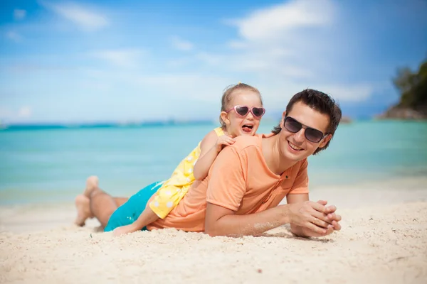 Joven padre y su adorable hijita acostada en la playa de arena blanca —  Fotos de Stock