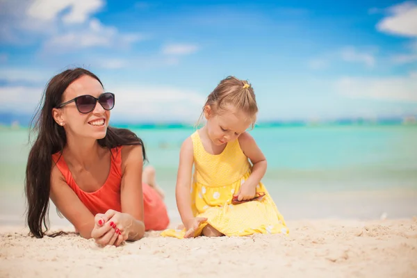 Young mother and her little daughter lying at tropical beach — Stock Photo, Image