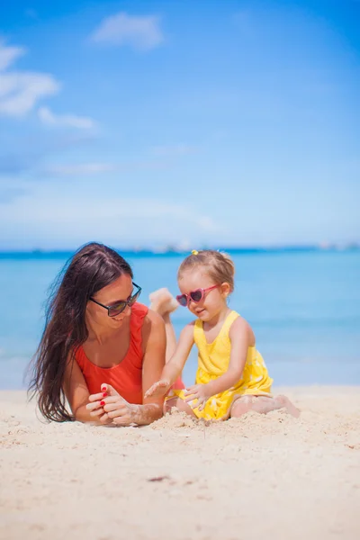 Ung mamma och hennes lilla dotter liggande på vit sandstrand — Stockfoto