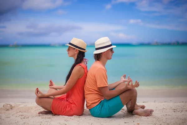 Ungt par njuter av varandra och yoga på en strand — Stockfoto