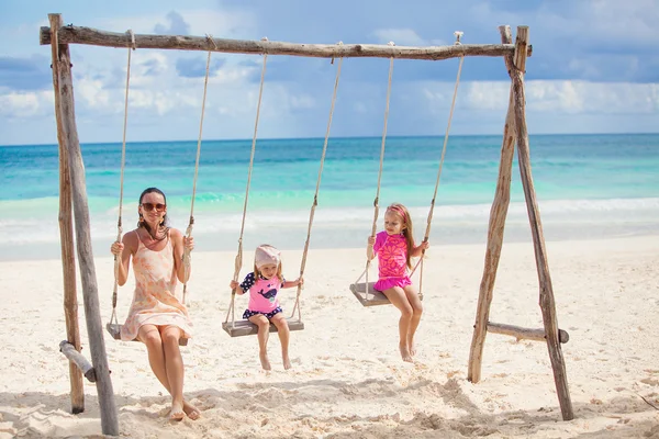 Young mother and her cute daughter swinging on a swing at the beach — Stock Photo, Image