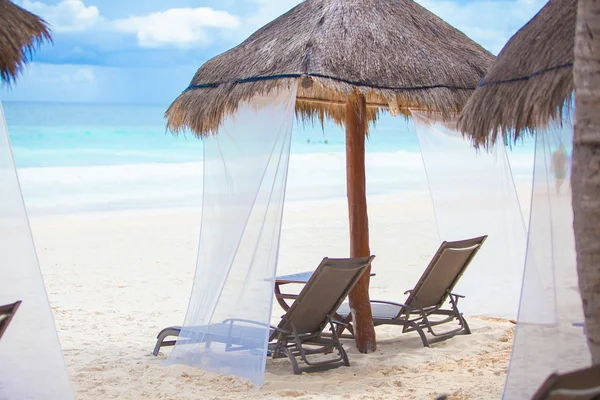 Leżaki plażowe parasole kryte strzechą na tropikalny plage — Zdjęcie stockowe