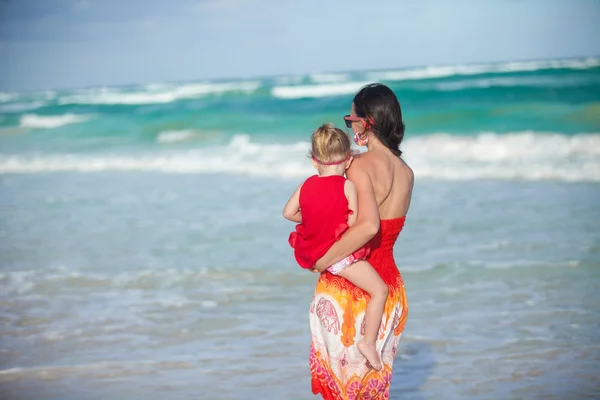 Achteraanzicht van moeder en dochter in rode jurk lopen op strand — Stockfoto