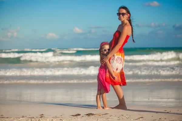 Trevlig ung mamma och hennes söta dotter gå på tropical beach — Stockfoto