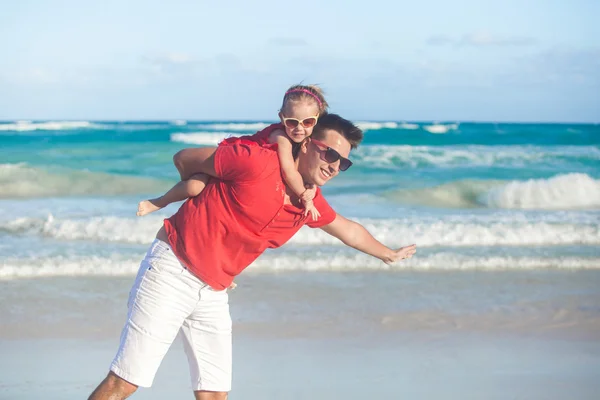 Junger Vater und seine entzückende kleine Tochter fliegen wie ein Vogel am tropischen Strand — Stockfoto