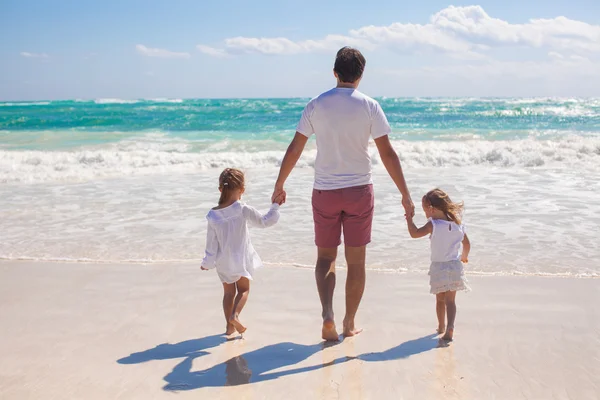 Rear view of father and his two cute daughters walking on white sand beach — Stock Photo, Image