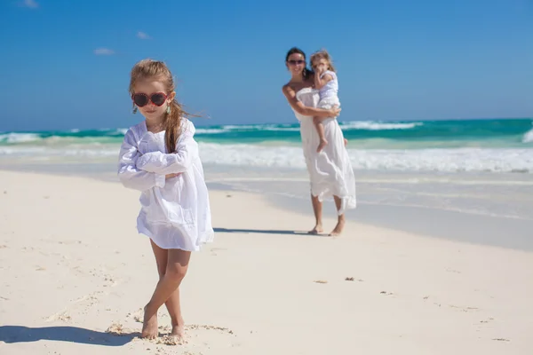 Portrait of adorable girl and her mother with little sister in the background at tropical beach — Stock Photo, Image