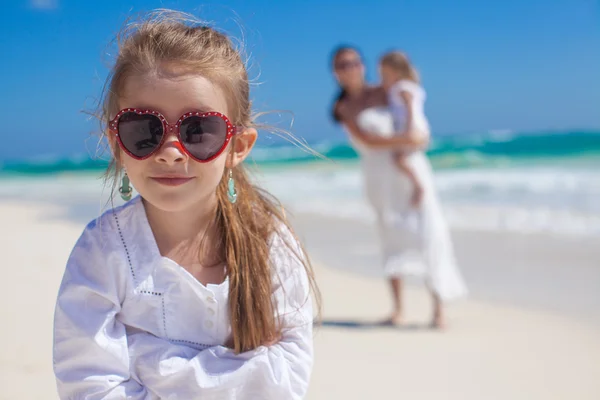 Portre sevimli tatlı kız ve annesi ile tropikal plaj arka planda küçük kardeş — Stok fotoğraf