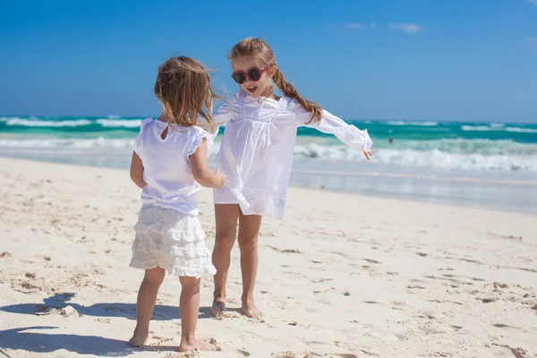 Zwei kleine Schwestern in weißen Kleidern amüsieren sich am tropischen mexikanischen Strand — Stockfoto