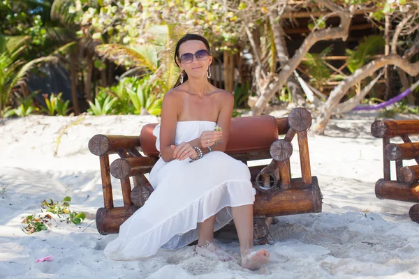 Young sexy woman sitting on wooden chair in exotic tropical resort — Stock Photo, Image