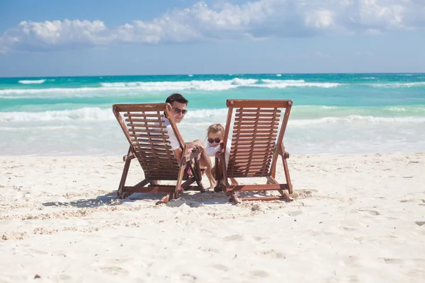 Young father and his wonderful daughter sitting on beach wooden chairs looking at camera — Stock Photo, Image