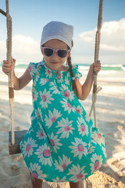 Beautiful little girl swinging on a swing outdoors — Zdjęcie stockowe