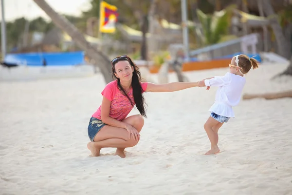 Close-up niña está sosteniendo a su joven madre en la playa — Foto de Stock