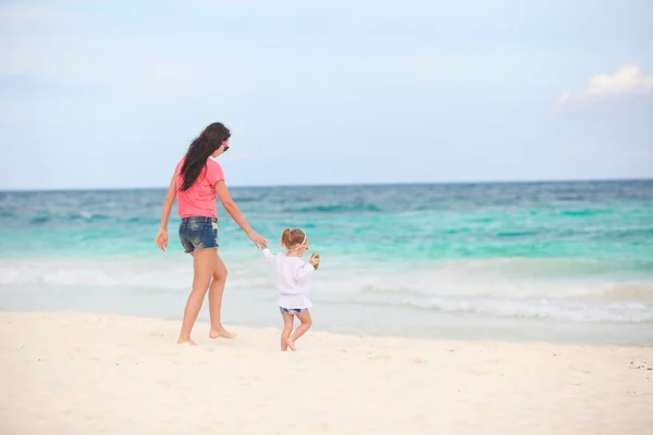 Young beautiful mother and her adorable little daughter running along the sea — Stock Photo, Image