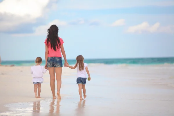 Vista posterior de la joven madre y sus hijas lindas caminando en la playa tropical — Foto de Stock