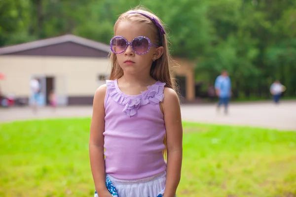 Чудесная девочка в солнцезащитных очках прогуливается по летнему парку — стоковое фото