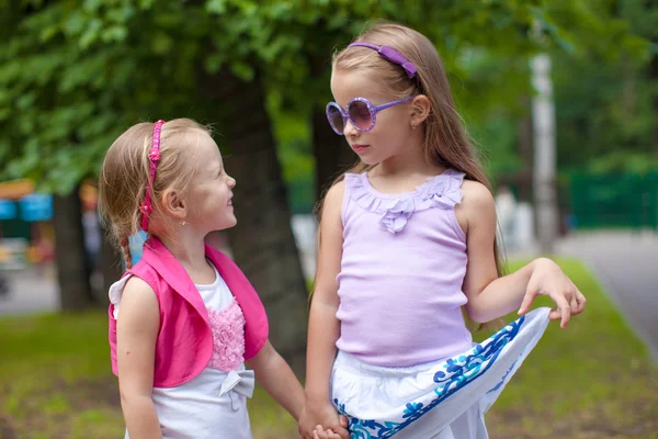 Two fashion cute sisters go hand in hand in the park — Stock Photo, Image