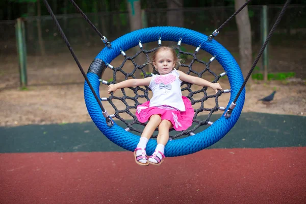 Little girl on swing at an amusement park — Stock Photo, Image