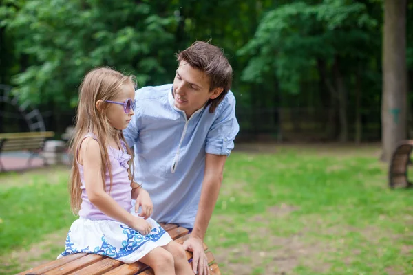 Young father with his cute daughter sitting on the wooden chair — Stock Photo, Image