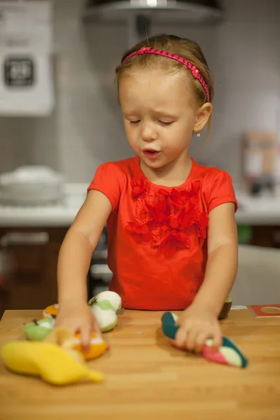 Niña jugando en la cocina con frutas y verduras —  Fotos de Stock