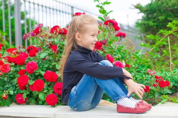 Menina bonito perto das flores no quintal de sua casa — Fotografia de Stock