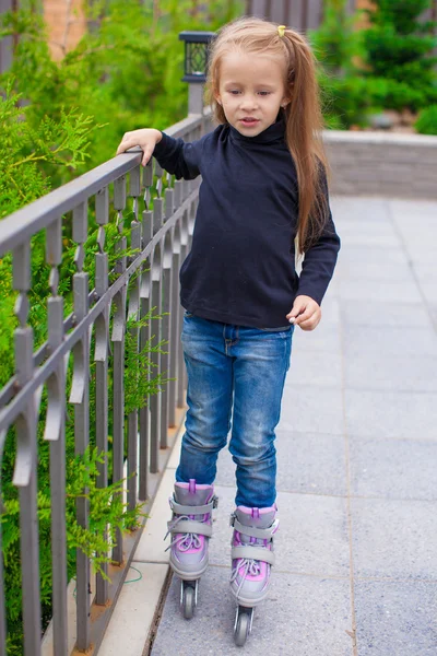 Pequena menina bonito em patins na frente de sua casa — Fotografia de Stock