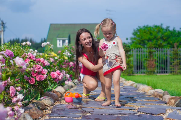 Jovem mãe com sua filha fofa se divertir no jardim hora de verão — Fotografia de Stock