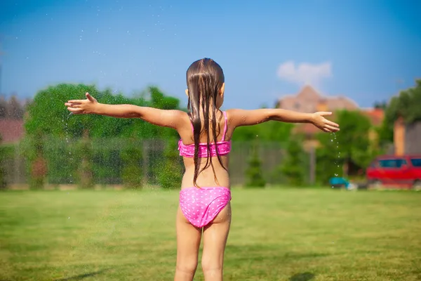 Vista trasera de la niña en traje de baño jugando y salpicando —  Fotos de Stock