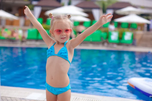 Beautiful little girl spread her arms standing near swimming pool — Stock Photo, Image