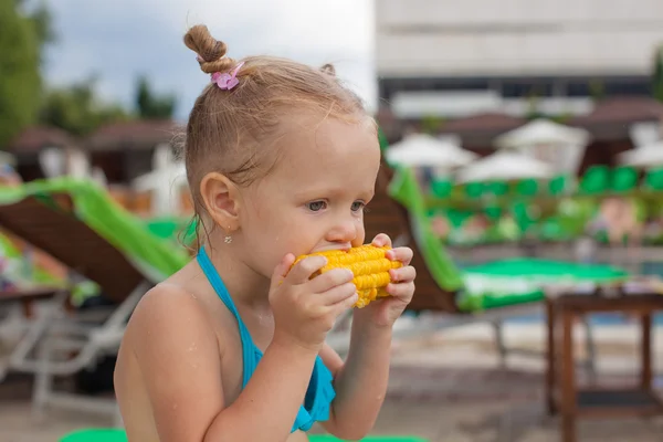 Carino bambina mangiare mais in piscina in vacanza — Foto Stock