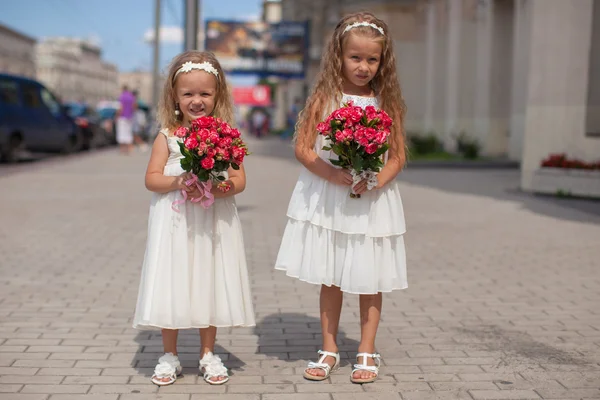 Duas irmãs encantadoras com belos buquês de rosas em suas mãos vão ao casamento — Fotografia de Stock