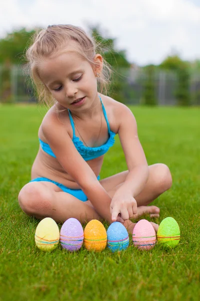 Küçük güzel kızın Paskalya yumurta yeşil çimenlerin üzerinde bulur — Stok fotoğraf