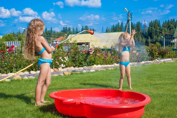 Two little sisters frolicing, splashing and having fun in their yard — Stock Photo, Image
